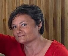 Mujer con pelo corto sonriendo frente a un fondo de madera.