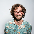 Mann mit Brille und Hawaii-Hemd lächelt in die Kamera.