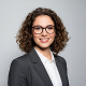 Porträt einer lächelnden Frau mit Brille und Anzug.