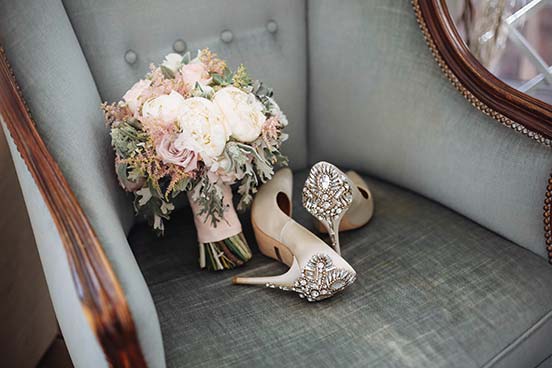 Bridal bouquet and bridal shoes on grey armchair