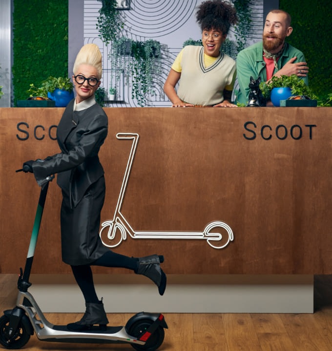 Two business owners in their e-scooter shop and a woman riding a scooter