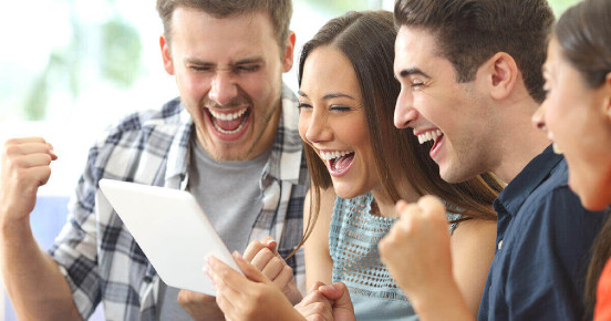 Group of people smiling whilst looking at a tablet screen